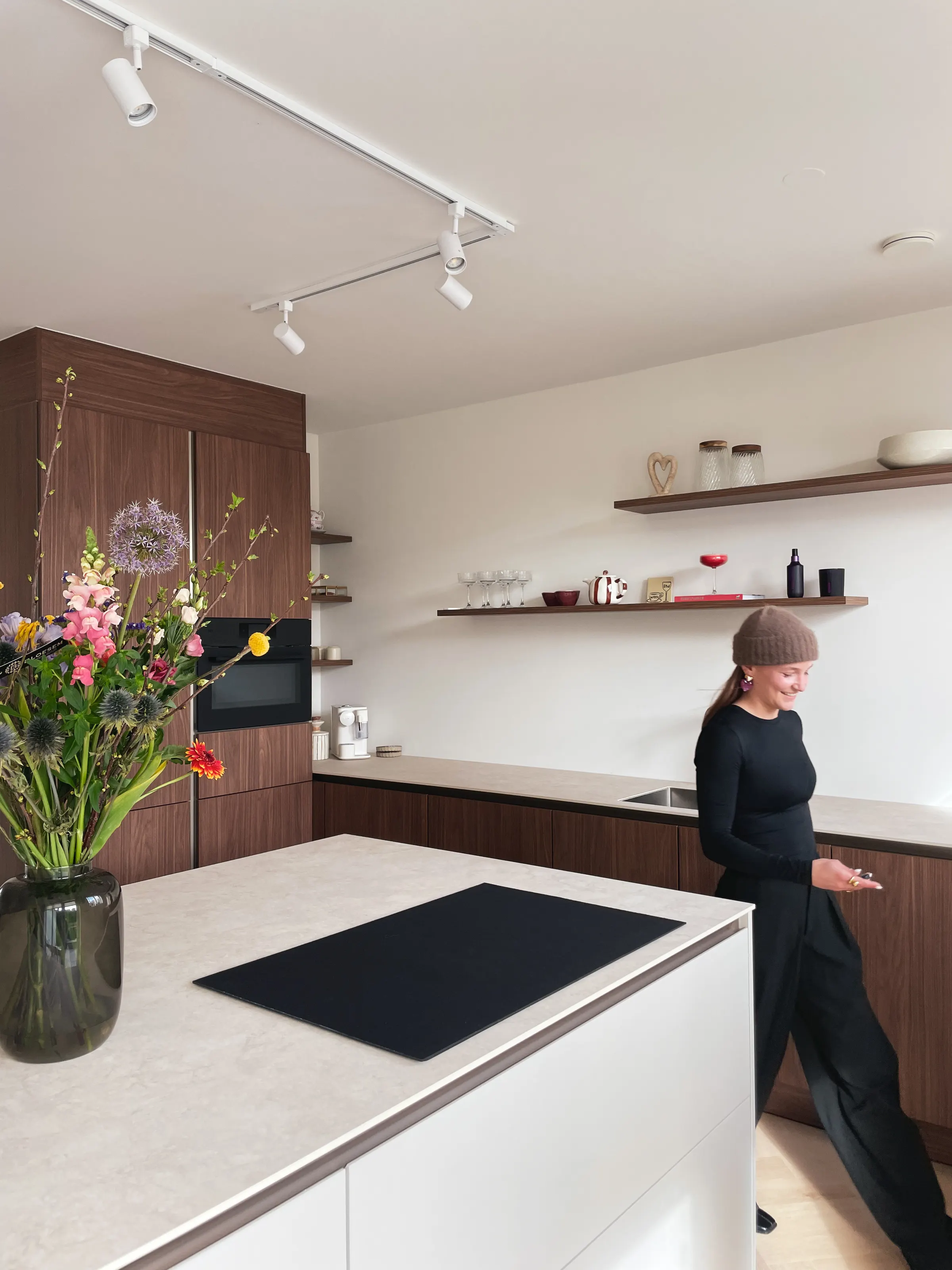 Lobke Meertens loopt door de keuken van notenhout met wit kookeiland in Woning Terneuzen