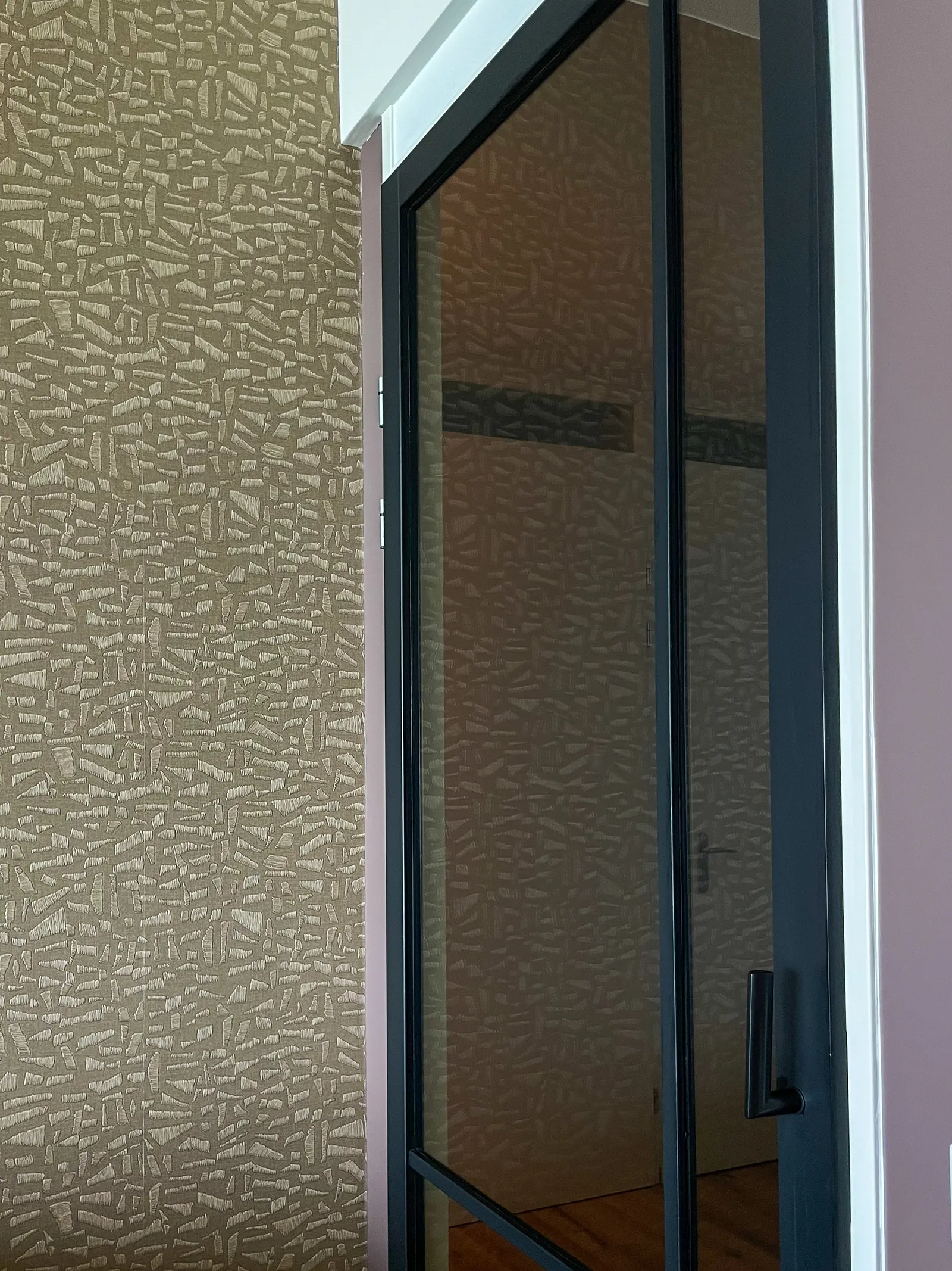 Stalen deur met glas naast een wand met grafisch behang