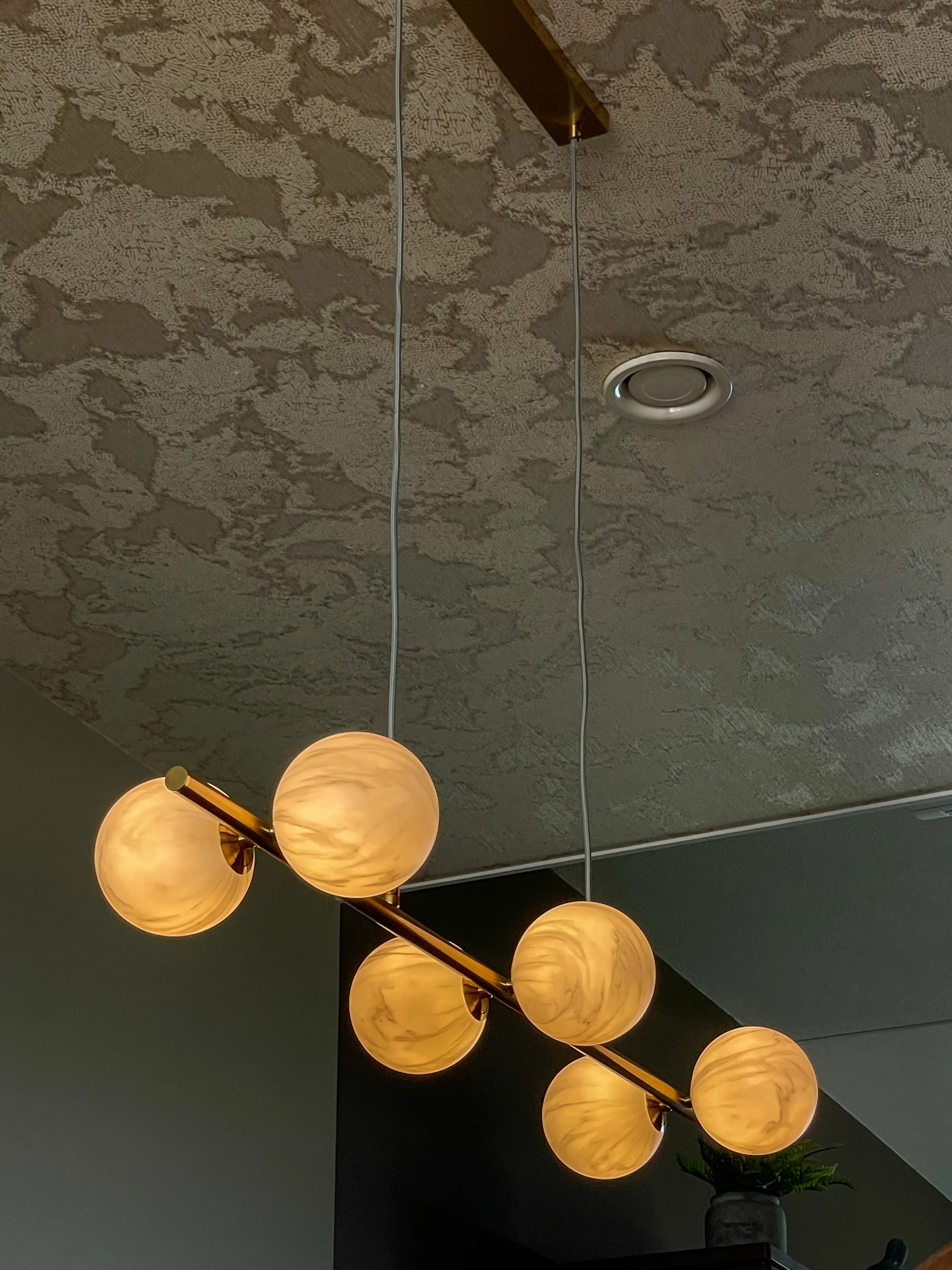Hanglamp met matglazen bollen onder het plafond met structuurbehang