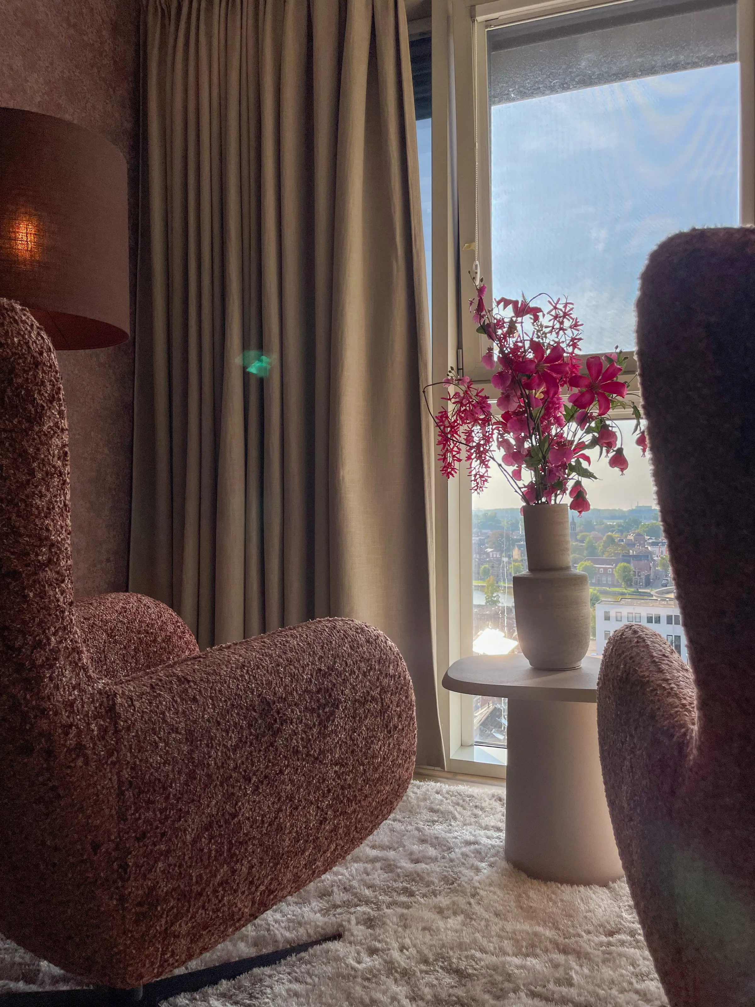 Fauteuil bij het raam met bloemen op een bijzettafel