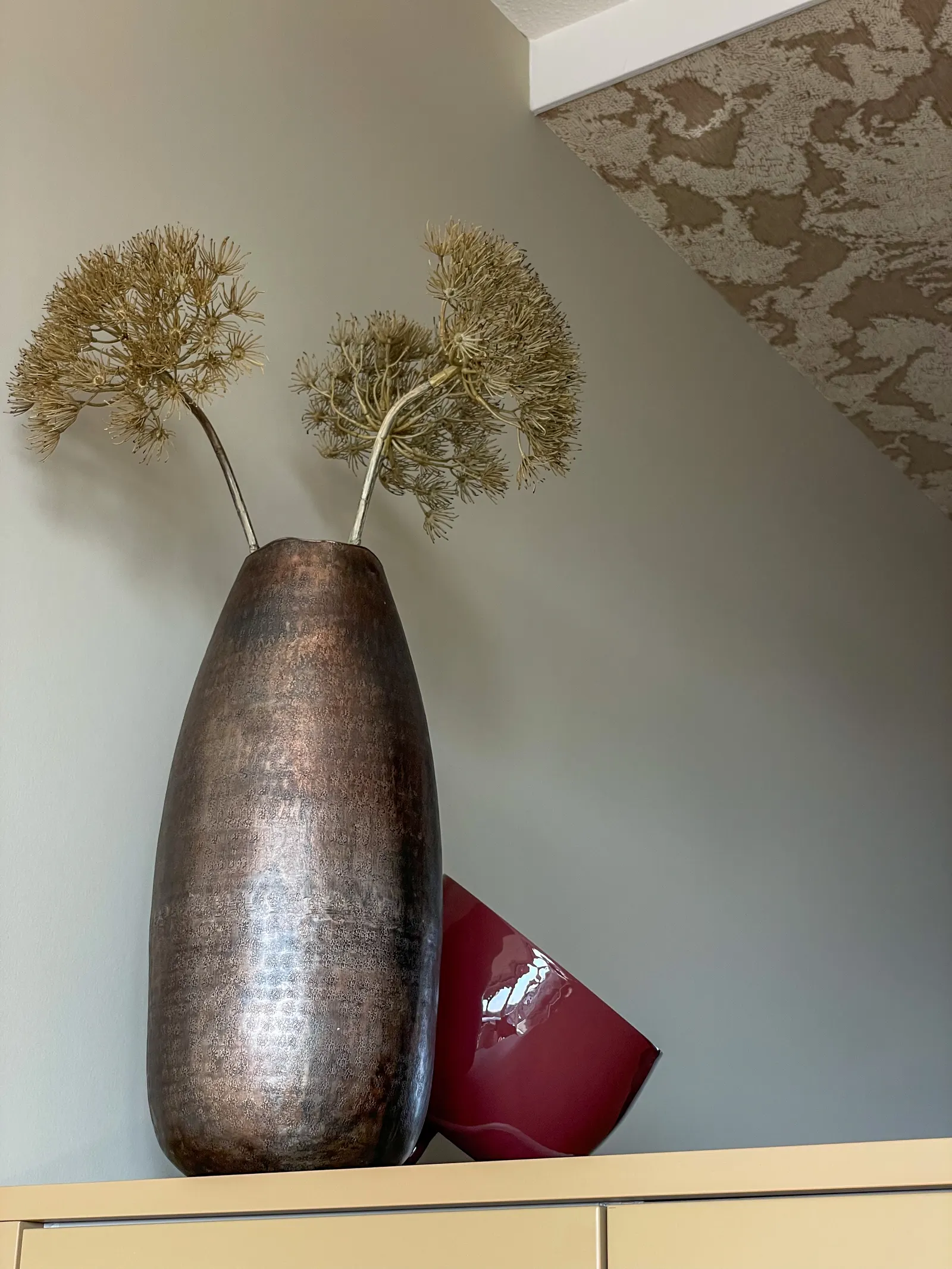 Bronzen vaas met gedroogde alliums op een kast