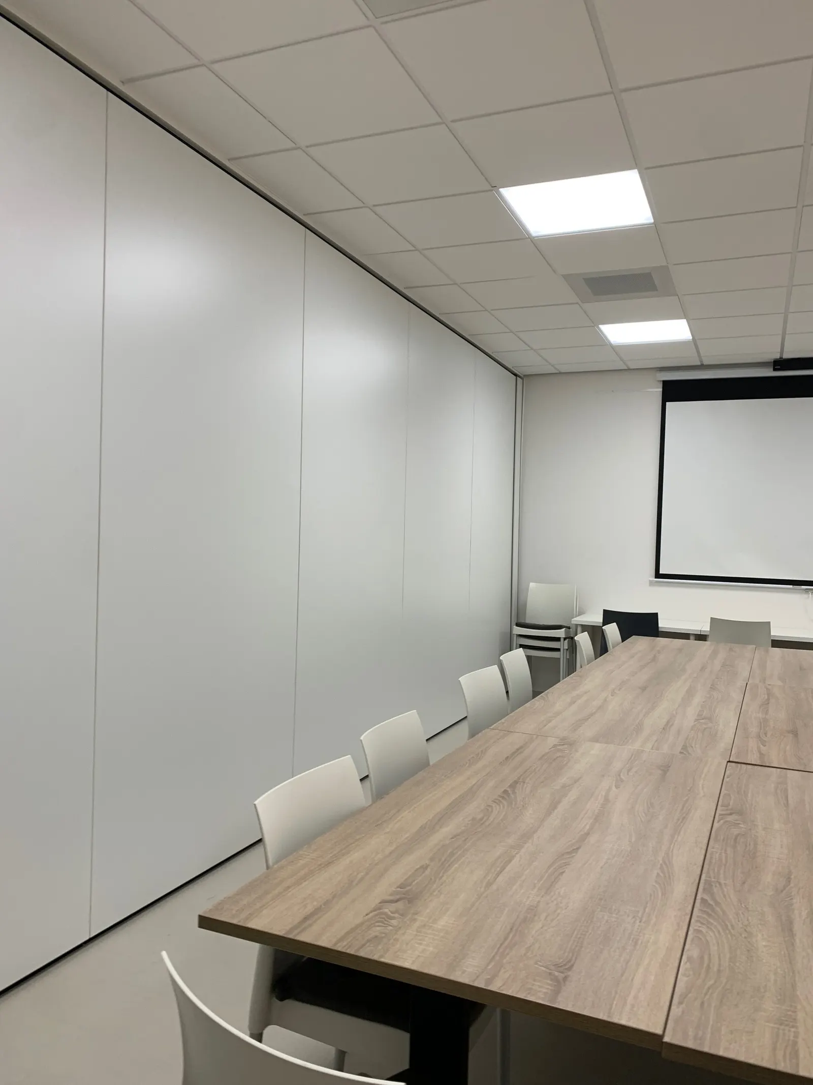 Witte scheidingswand met beamerscherm in de vergaderzaal van de bibliotheek, voor de verbouwing