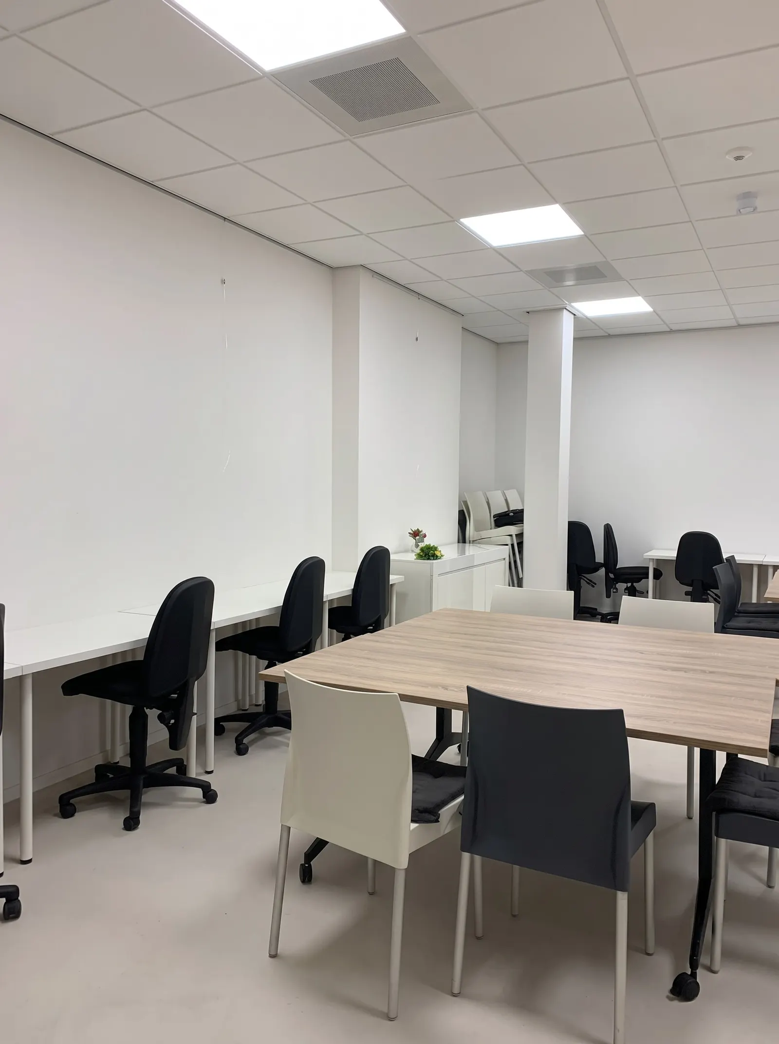 Vergaderzaal in de bibliotheek van Terneuzen voor de verbouwing: witte wanden, systeemplafond en zwarte bureaustoelen