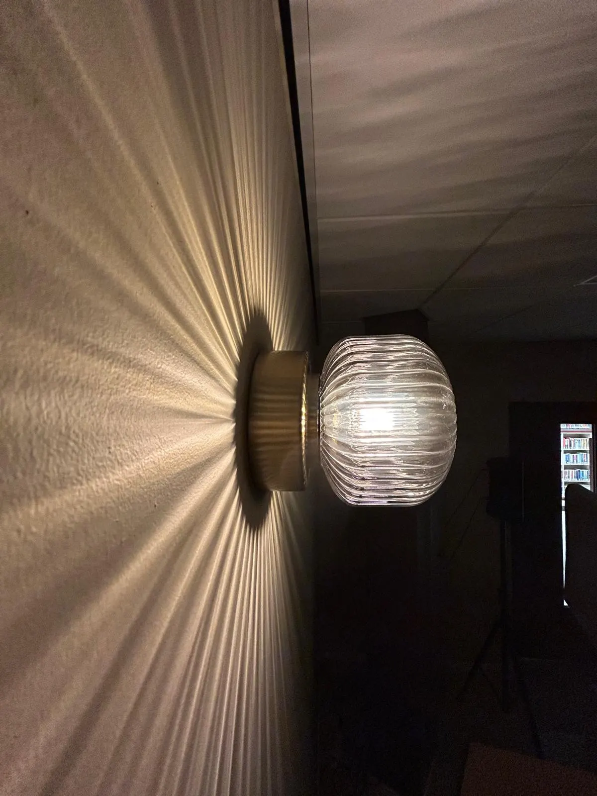 Glazen wandlamp die een stralenschaduw op de wand werpt