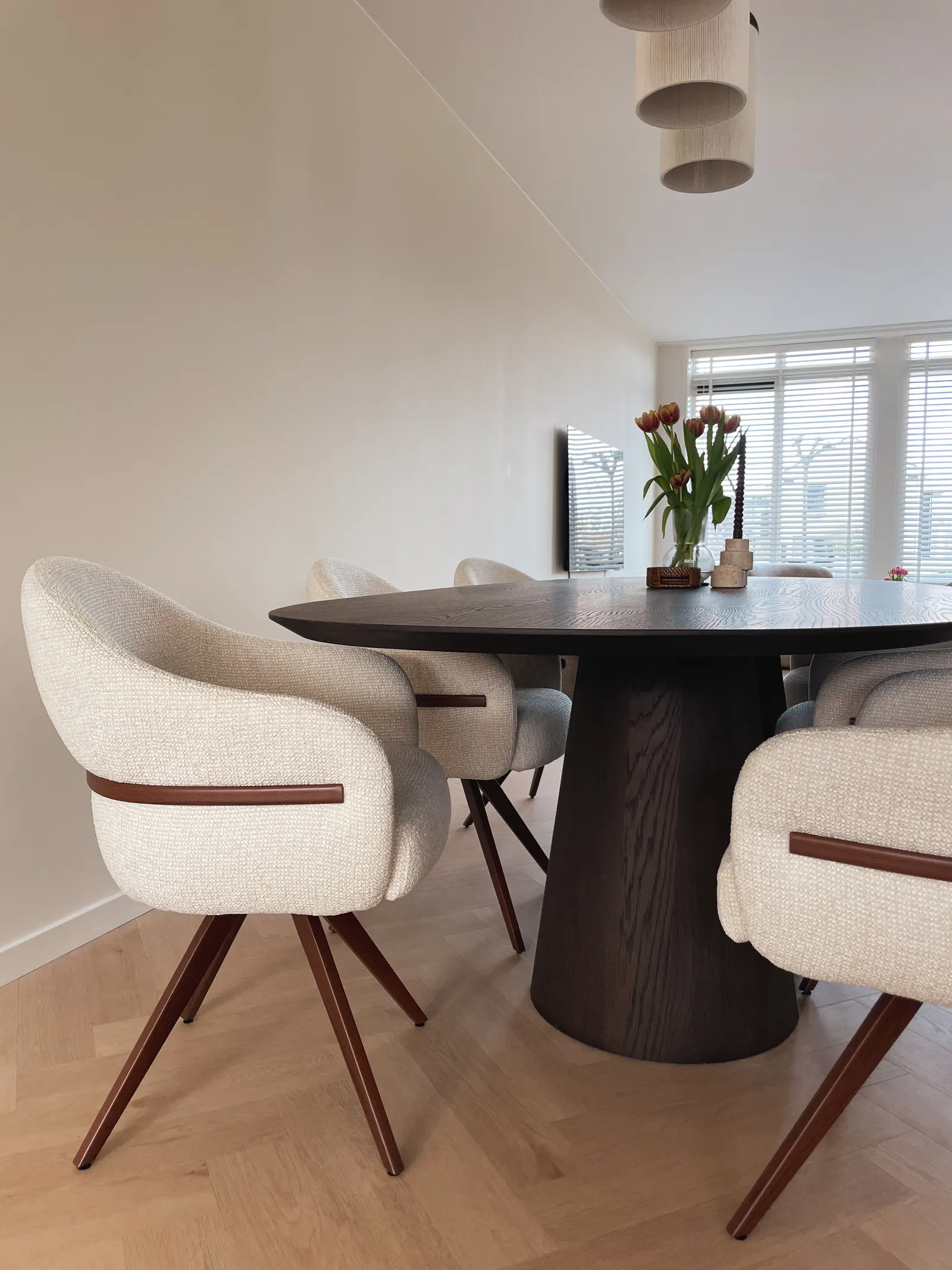 Ovale eettafel met bouclé stoelen op visgraatvloer